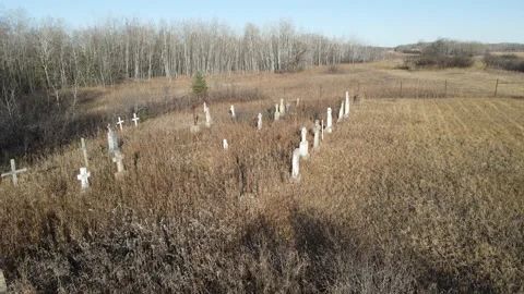 Drone moving slowly forward over an abandoned overgrown cemetery with dry grass  Stock Footage 220451499