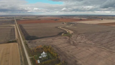 Drone moving slowly high over a late autumn prairie farmland with church Stock Footage 141830550