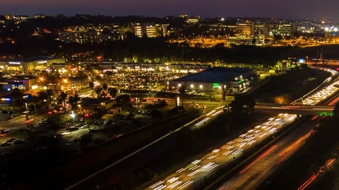 Drone night hyperlapse shows busy freeway and shopping plaza Stock Footage 85643586