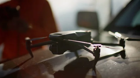 Drone with open propellers resting on a vehicle's hood. Drone with Extended Stock Footage 265030593