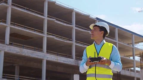 Drone operator holding remote controller. Professional builder in helmet and Stock Photos