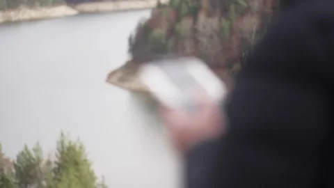 Drone operator using remote controller flying the quadcopter  above mountian  Stock Footage 307953119