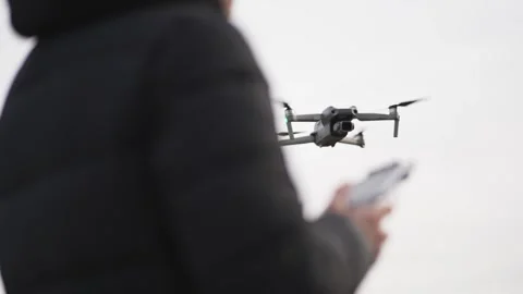 Drone operator using remote controller flying the quadcopter  above mountian  Stock Footage 333721487