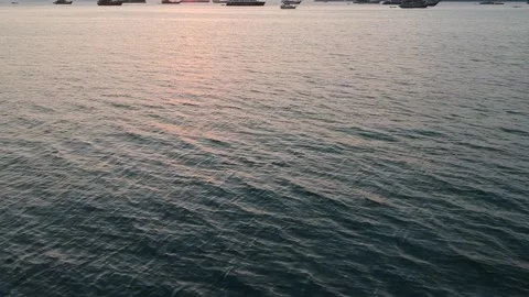 Drone, orange sunset reflections on smooth ocean, boats on horizon, Komodo I Stock Footage 131437034