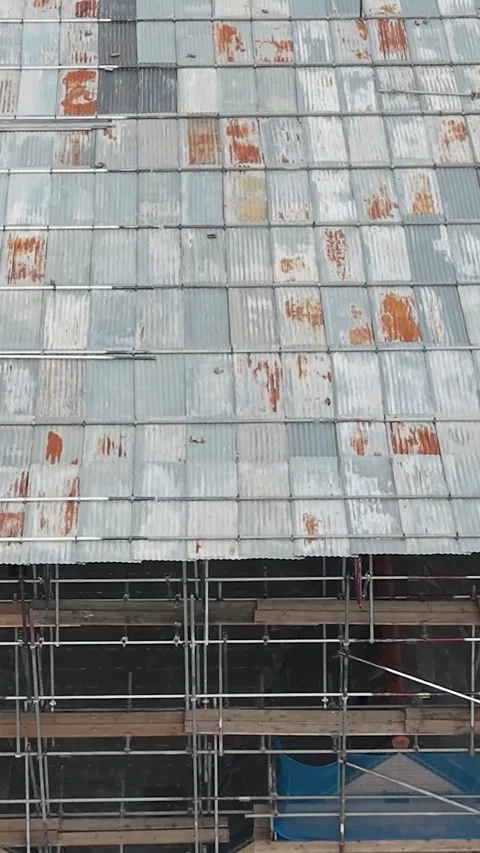Drone orbit of apartment block with scaffolding, blue netting and corrugated Stock Footage 340333777