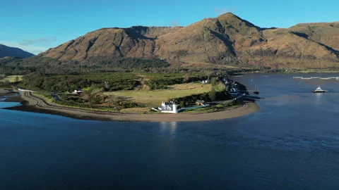 Drone orbit around Corran Point with lighthouse on sunny day Stock Footage 330591412