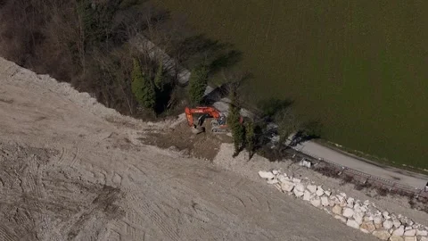 Drone orbit around excavator performing riverbank stabilization and earthworks Video stock 340763380