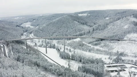 Drone orbit around highway bridge with moving cars in snowy forest landscape Video stock 332011478