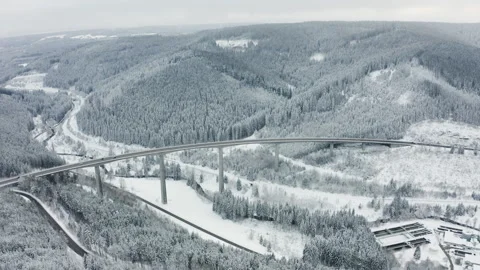 Drone orbit around highway bridge with moving cars in snowy forest landscape Video stock 332046358
