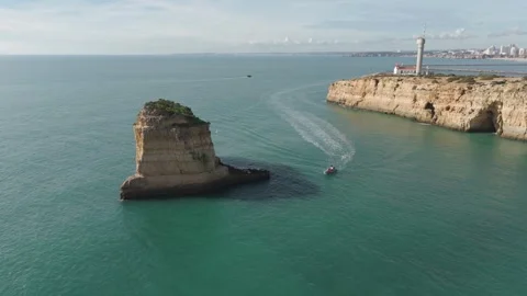 Drone Orbit Around Isolated Cliff with Lighthouse in Background, Ferragudo Stock Footage 328337799