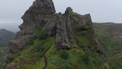 Drone orbit around a jagged mossy cliff revealing a vast volcanic canyon Stock Footage 324966536
