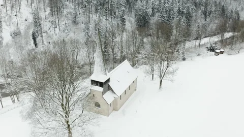 Drone orbit around small rural church in snowy forest landscape Video stock 332002114