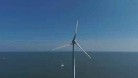 Drone orbit around wind turbine over open water with sailboats Stock Footage 339682362