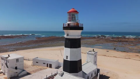 Drone Orbit of Lighthouse with Ocean, Beach, Sand, Blue Sky, and Green Landscape Stock Footage 306255104