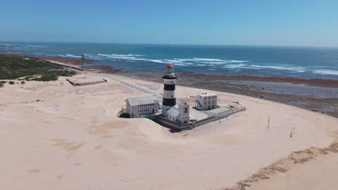 Drone Orbit of Lighthouse with Ocean, Beach, Sand, Blue Sky, and Green Landscape Stock Footage 306255754