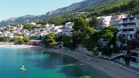 Drone Orbit Over Brela Beach With Paddleboarder and Island View – 4K Stock Footage 313900976