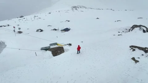 Drone orbit revealing Orange jacket Traveller at snow-covered Phase 2 Gondola st Stockbeeldmateriaal 333801473