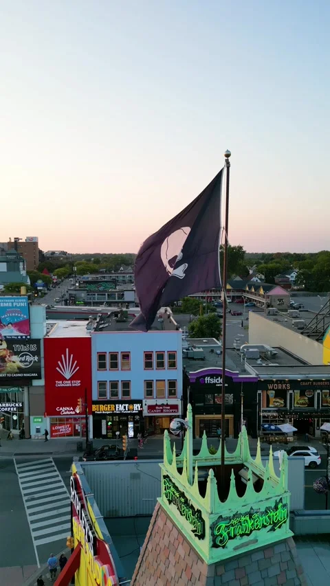 Drone Orbit Shot of Pirate Flag with Sun Reveal at Clifton Hill Amusement Park, Video stock 330450810
