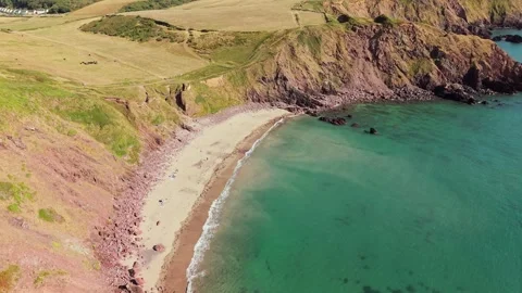 Drone Orbit of Westdale Bay Sandy Beach and Red Cliffs, Wales Stock Footage 346077095