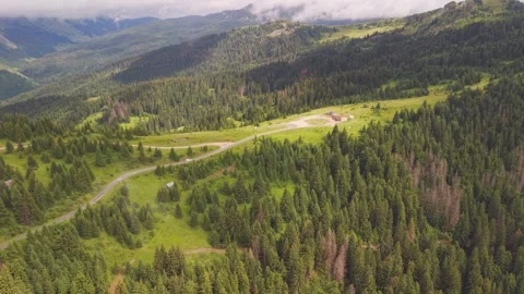 Drone orbital shot of a winding mountain pass road, isolated building, and pine Stock Footage 342324347