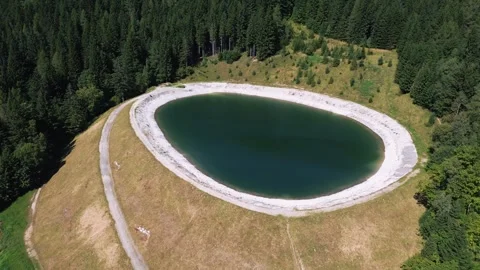 Drone Orbiting Around Small Artificial Lake in Mountain Forest Stock Footage 323607574