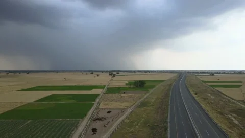 Drone orbiting around storm over a highway and agricultural fields Stock Footage 202226250