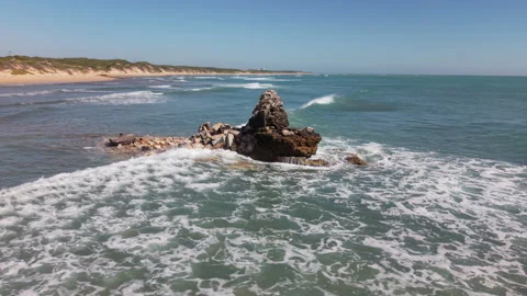 Drone Orbiting Crumbled Beacon in Shallow Sea with Waves Crashing Against Rocks, Stock Footage 306321564