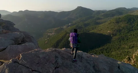 Drone orbiting a female climber with backpack standing on the edge of the cliff Stock Footage 149268027