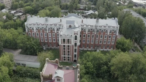 Drone orbiting historic brick building above trees Video stock 333012283