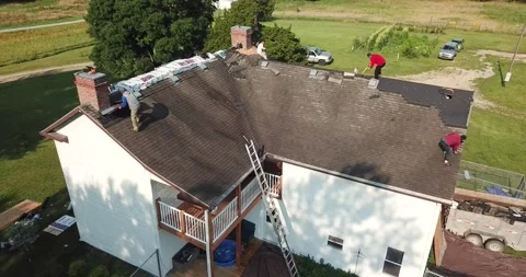 Drone Orbiting over Roofers Removing and Tossing Shingles Stock Footage 202052410