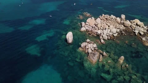 Drone orbiting rocks in blue sea in 4K Video stock 153347299
