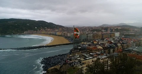 Drone orbiting view of San Sebastian with Basque Flag flapping in Stock Footage 122949429