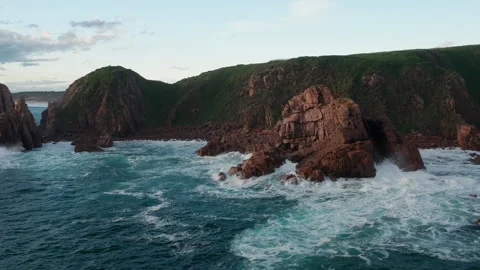 Drone Orbits Around Red Rocky Granite Coast As Blue Waves Crash Against Cliffs Stock Footage 248947178
