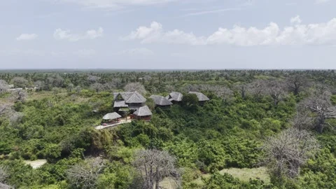Drone orbits left in 360 around hilltop resort overlooking baobab forest Stock Footage 344106607