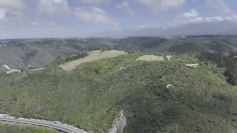 Drone orbits to the left high over paragliders on a sunny day on Garden Route Stock Footage 326769788