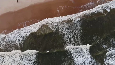 Drone over breaking waves green sea. Two people waking in the sand. Vídeo Stock 117406420