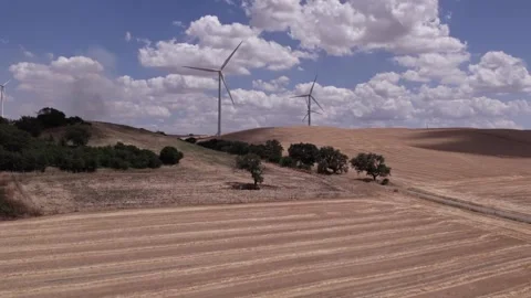 A drone over farmers' fields on a cloudy day. Wind turbines are operating in the Stock Footage 334327507