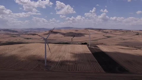 A drone over farmers' fields on a cloudy day. Wind turbines are operating in the Stock Footage 334368216