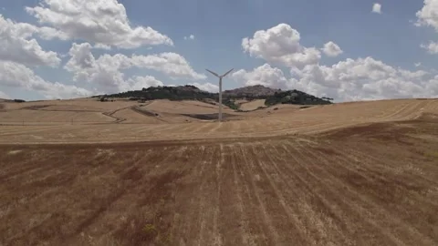 A drone over farmers' fields on a cloudy day. Wind turbines are operating in the Stock Footage 334369325
