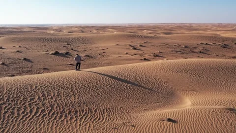 A drone over a lone man walking on a sand dune in the desert. Dubai, a sunny Stock Footage 311804791