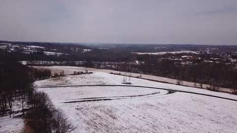 Drone over melted snow covered field homes and trees on horizon 스톡 동영상 104307536