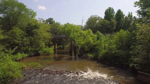 Drone over muddy river bridge green trees Stock Footage 85377028