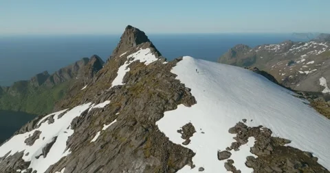 Drone Over Munken Summit with Hikers Crossing Snow Patch in Lofoten Norway Vídeos de archivo 334345667