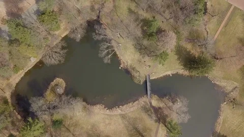 Drone over small lake and trees with small foot bridge Stock Footage 106059554