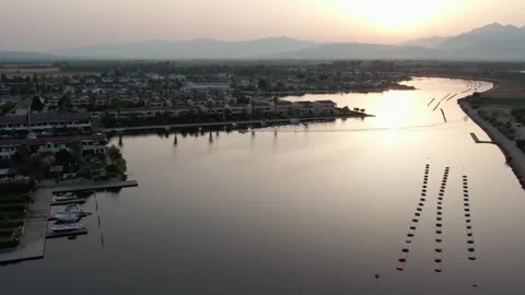 A drone over a small town on a lake. Marinas, Cloudy summer sunset. Sibari, Stock Footage 334427740