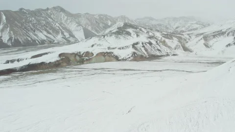 Drone Over Snow Covered Mountains With Braided River Stock Footage 168774258