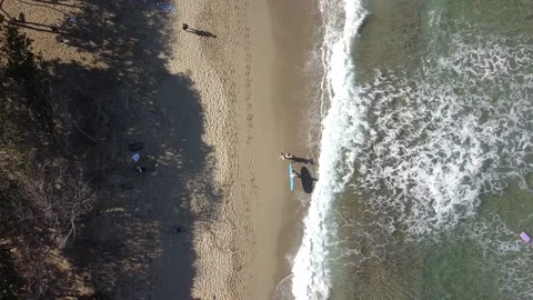 Drone over surf beach with surfers walking and surfing Stock Footage 232555769