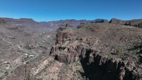 Drone Over Volcanic Mountain Ridge Revealing Distant Valley and Village Stock Footage 309943606