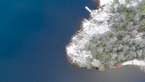 Drone overhead flying inside clouds over frozen shore, trees and a tranquil lake Stock Footage 104505643