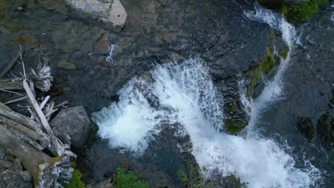 Drone overhead shot flies over a flowing waterfall Stock Footage 318476989